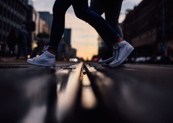 people crossing the street surrounded by buildings and shops