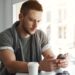 closeup guy sitting table cafe texting message