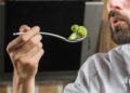 close up male chef holding broccoli spoon with his hand